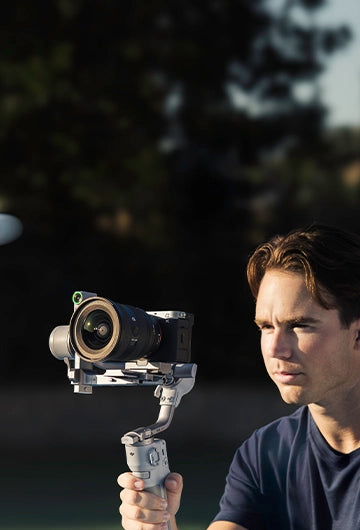 A man filming a tennis player using a DJI RS 4 Mini